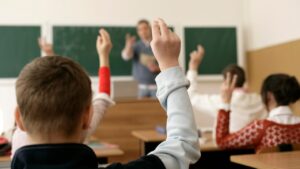 Leerlingen steken hun hand op in de klas, passend bij schoolfoto AVG en privacy van leerlingen op school
